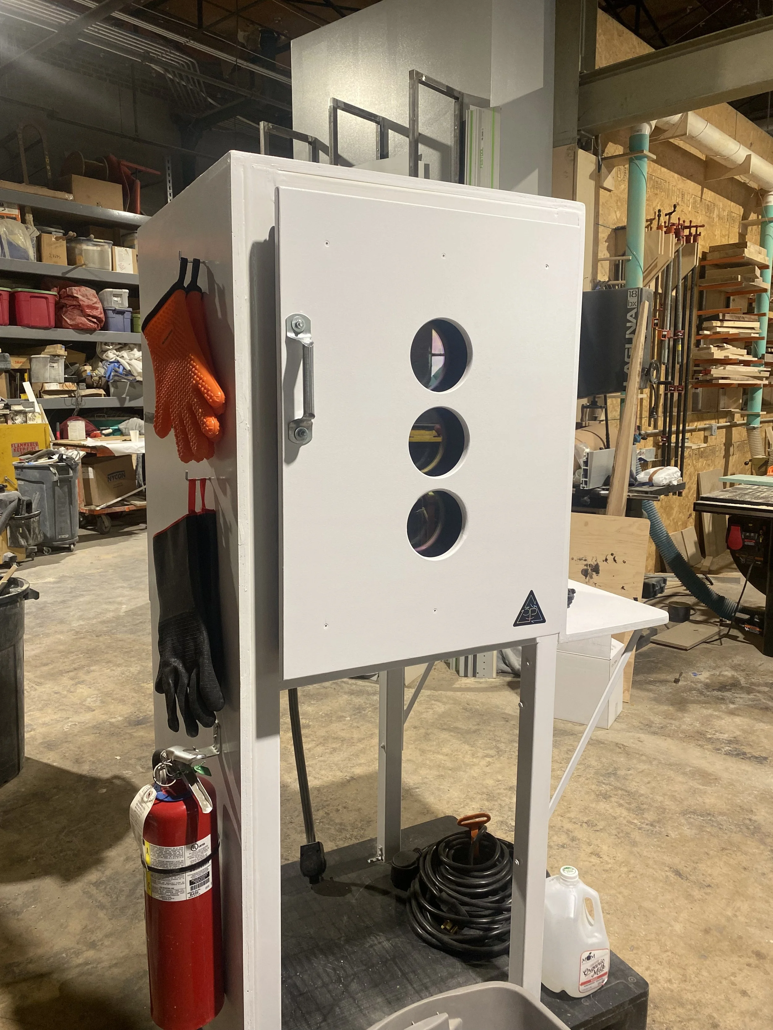 The 3P processing station: a palletized white cabinet with three porthole windows and the 3P triangle logo, safety gear hanging on its side