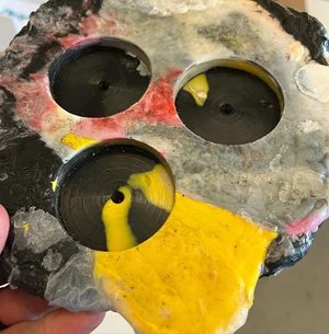 A finished mold piece in black, red, and yellow, held up in someone's hand