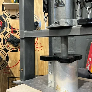 Close-up of the press pushing black plastic into a cylindrical mold