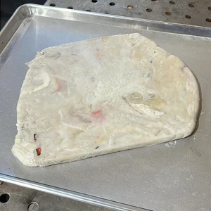 A flattened sheet of melted, fused plastic film on a metal baking tray